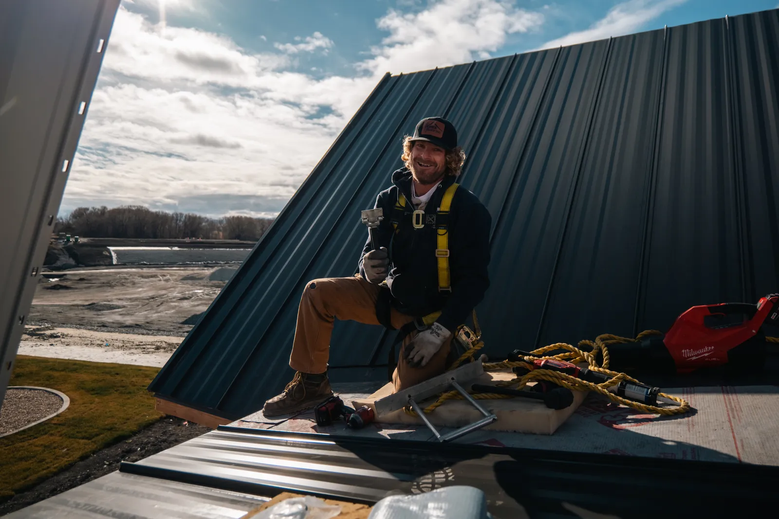 Homer Roofing crew member installing black standing seam metal roofing on a new build in Northern Utah