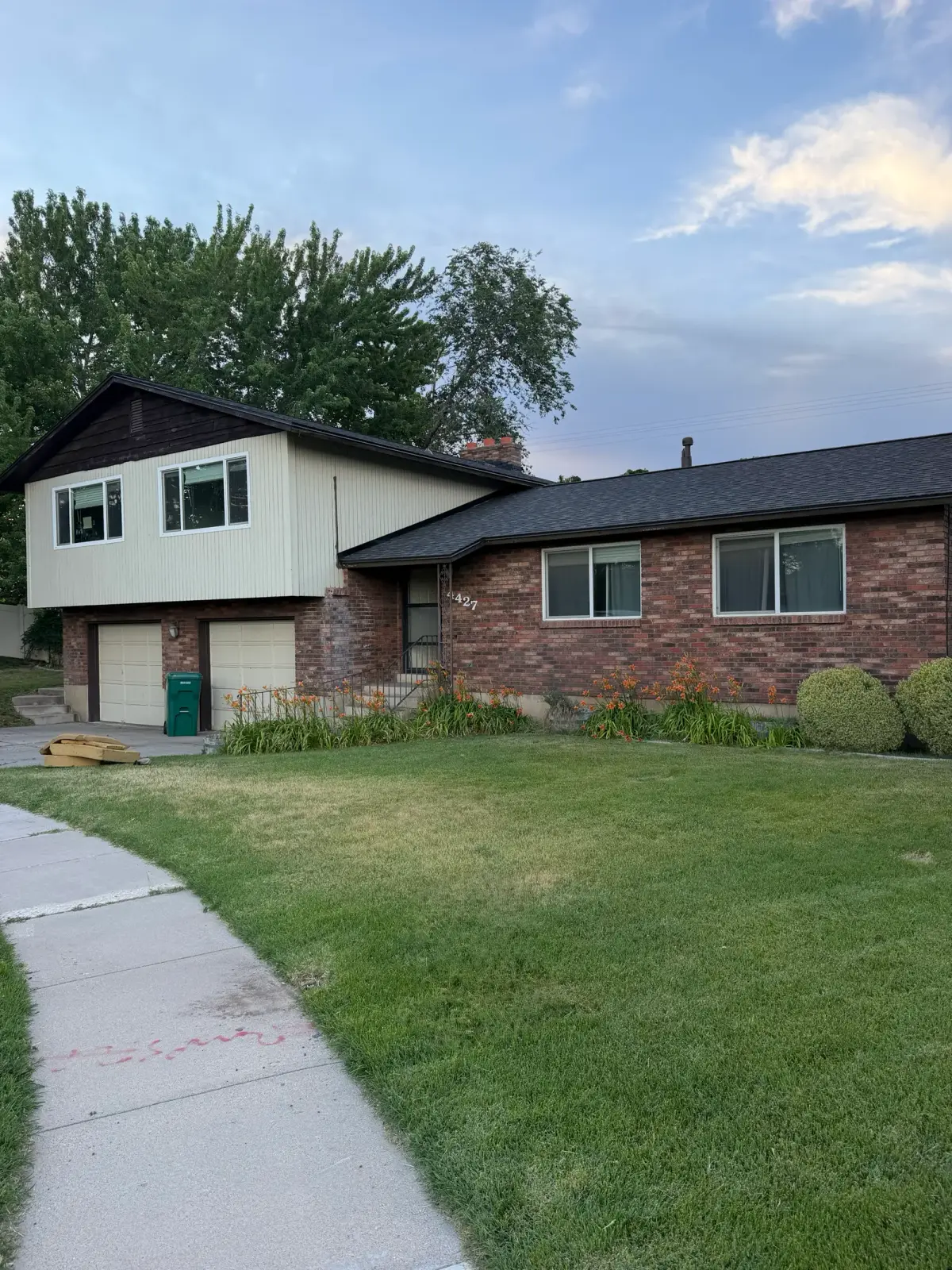Street view of a completed asphalt shingle roof replacement on a Roy, Utah split-level home by Homer Roofing