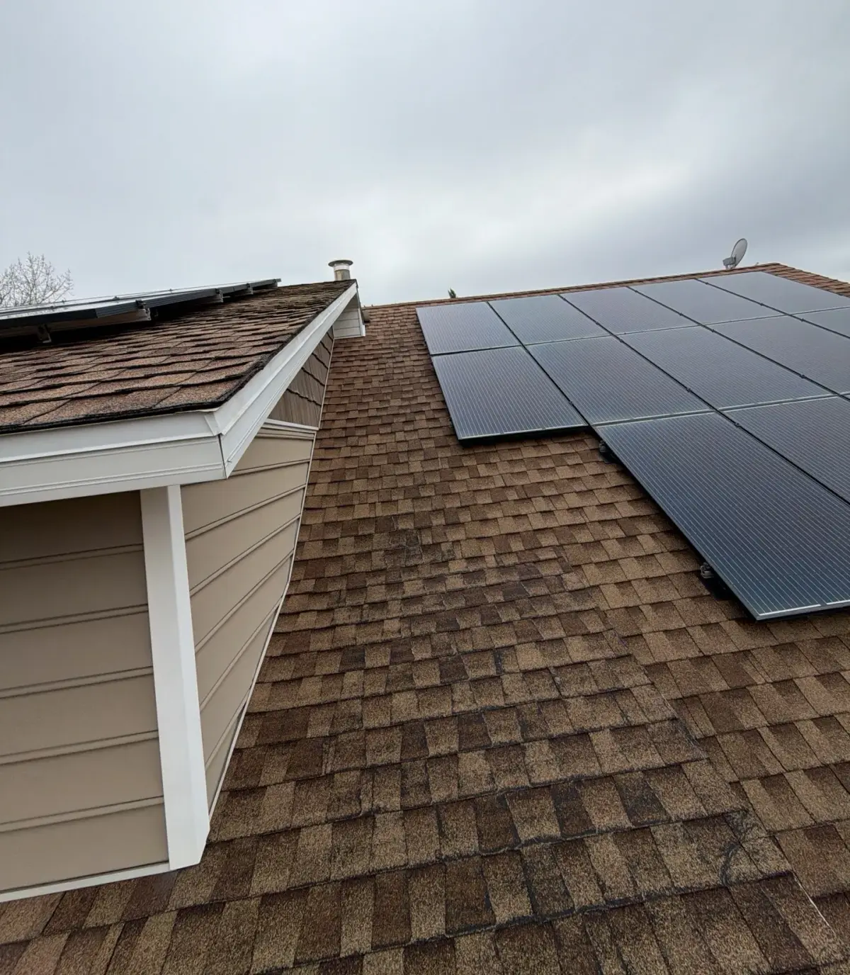 Weathered-wood shingle roof reinstalled around rooftop solar panels on a Roy, Utah home by Homer Roofing