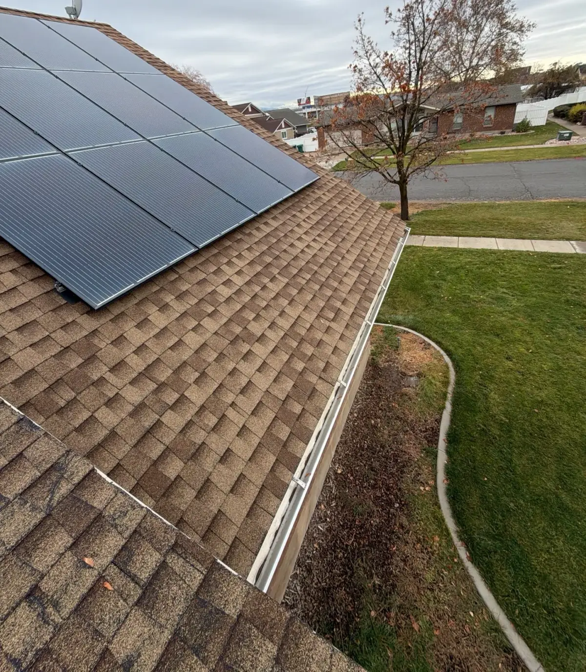 Completed asphalt shingle roof and solar array with new gutters on a Roy, Utah home by Homer Roofing