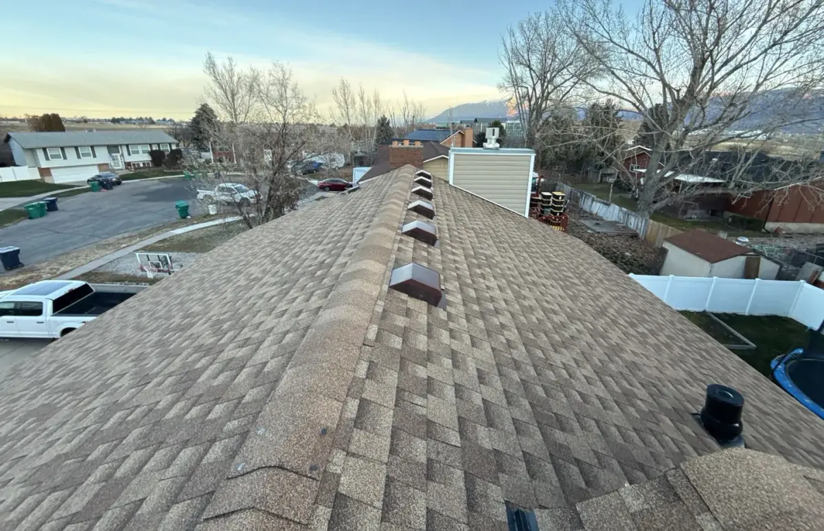 Ridge-line view of a new weathered-wood shingle roof with ridge vents on a Roy, Utah home by Homer Roofing