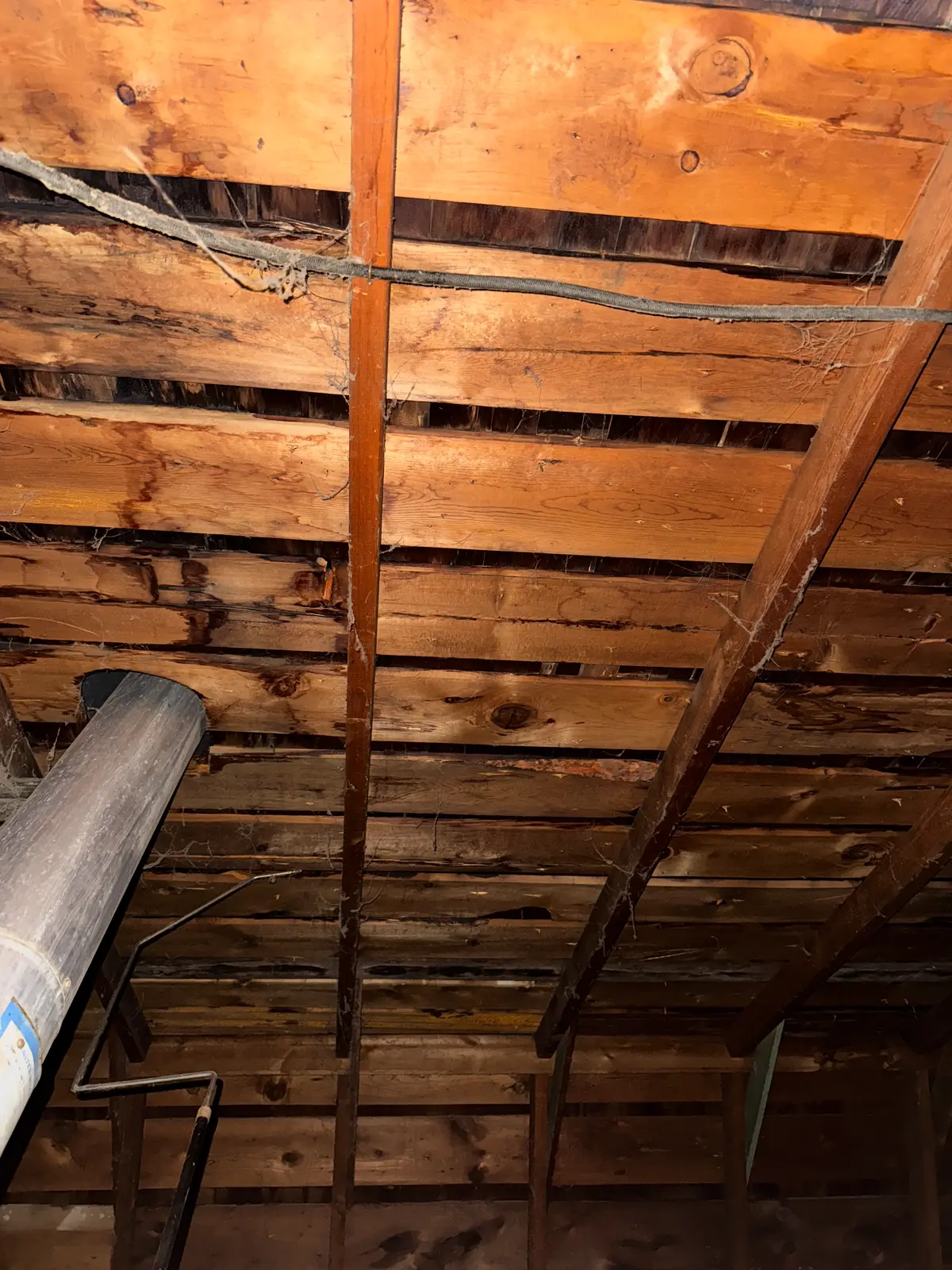 Spaced plank decking viewed from the attic of a Utah home showing gaps between boards